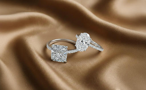 Ibling Jewels and Dvik Jewels lab grown diamond engagement rings in cushion and oval cuts on satin background