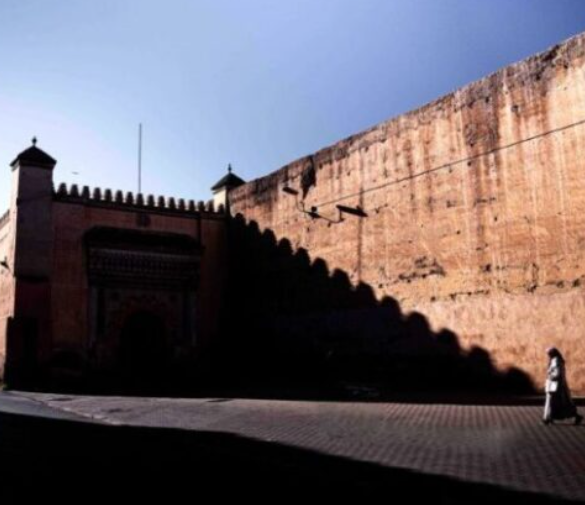 Cinematic photo of a person walking past a massive city wall in Morocco, a scene perfect for Moroccan photo tours.
